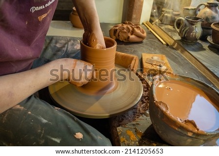 A master potter in an old craft workshop professionally forms a pot of clay with his hands