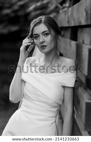 Portrait of a beautiful bride near a wooden wall with a hand near her hair. Black and white photo. High quality photo