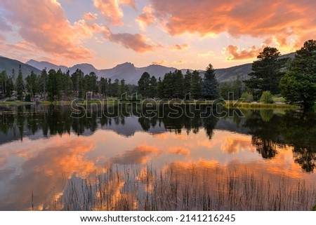 Summer Sunset at Sprague Lake - A panoramic Summer sunset view at Sprague Lake, with high peaks of Continental Divide rising at shore, Rocky Mountain National Park, Colorado, USA. Royalty-Free Stock Photo #2141216245