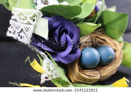 Easter motifs on a black background. Easter decorations in close-up. Wicker wreath with colourful eggs. Arrangement in eggshell on straw. Clay egg with chicken inside. Symbols of life, happiness.