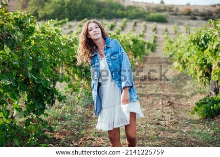 beautiful woman in a dress picks grape berries