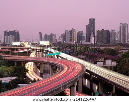 long exposure on super highway showing long trails and colorful lines on the road surface with big city background