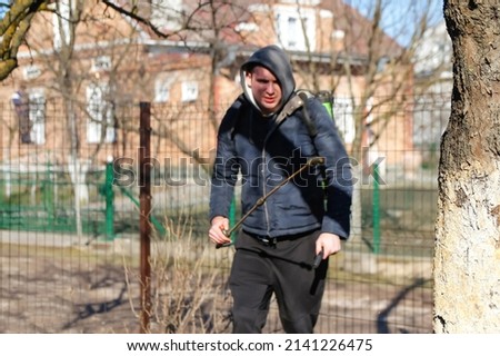 Organic ecological agriculture. Defocus farmer man spraying tree with manual pesticide sprayer against insects in spring garden. Agriculture and gardening. Chemical spraying.Young farmer Out of focus.