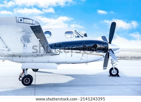 Small business plane parking at the airport ground with cloudy blue sky background, ready for flying across the world in concept of travel and vacation. Side view of air transportation.