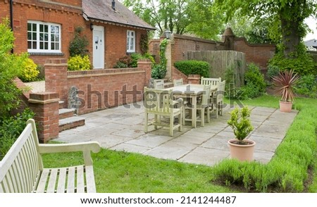 Garden patio with stone slab paving in a landscaped back garden. Large UK heritage house or country home