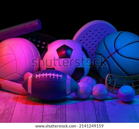Sports equipment, rackets and balls on hardwood court floor with neon light background. Horizontal education and sport poster, greeting cards, headers, website
