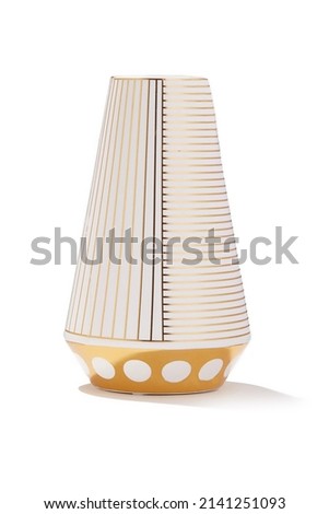 Subject shot of a white glossy vase made of glazed porcelain with golden stripes and polka dots. The designer glossy vase with a golden glaze is isolated on the white background.