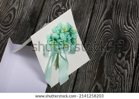 Homemade greeting card in green tones. Envelope for a postcard. On pine boards.