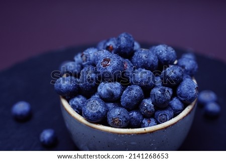 Blueberries in bowl on black slate background. Copy space for text, top view. water drops on blueberries .