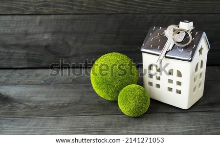 Model of a house, a bunch of keys to a new property.  Infrastructure greening.  Front view photography, real estate agency concept, eco houses.  Close-up.  Space for copy text, wooden background.