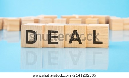 word deal on wooden cubes on blue background. the inscription on the cubes is reflected from the surface. business concept.