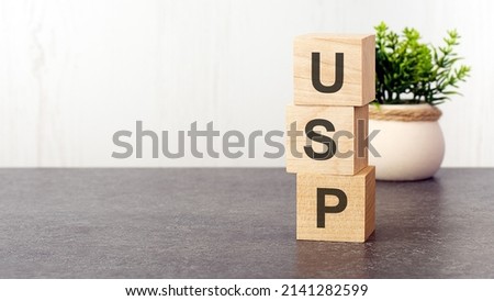 letters of the alphabet of USP on wooden cubes, green plant, white background. USP - short for Unique Selling Proposition