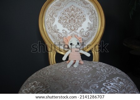beautiful cute knitted croceted toy unicorn of white color with eyelashes in a knitted peach dress in the interior of pastel colors