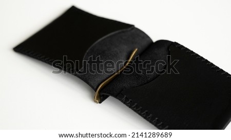 Open black men's money clip handmade leather wallet. Empty money clip wallet with a two pockets for cards lies on a white table. Selective focus, copy space.