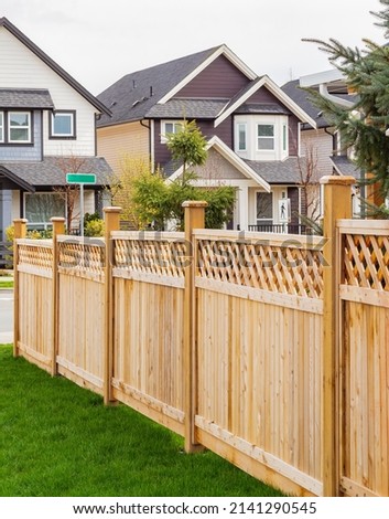 Nice wooden fence around house. Wooden fence with green lawn and trees. Street photo, nobody, selective focus Royalty-Free Stock Photo #2141290545