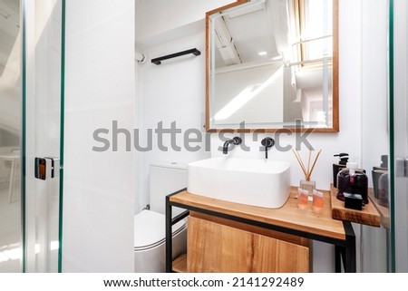 Bathroom with white porcelain sink on wooden cabinet and mirror with matching frame
