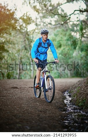 Keeping fit and enjoying nature. Shot of a male cyclist riding along a mountain bike trail.