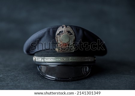 A navy blue police hat cap in front of a navy blue background with bokeh.