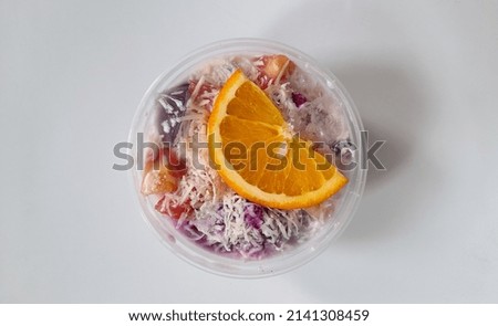 Auto-focus background objects at the middle of the picture or at the orange as a topping of the fruit salad with white background 