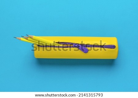 Yellow pencil case with three yellow pencils on a blue background. The minimum concept of storing school supplies. Flat lay. Royalty-Free Stock Photo #2141315793