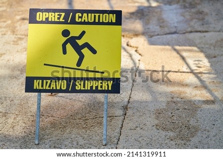   Sign with the inscription Caution slippery in Croatian and English in the old town of Krk in Croatia                              