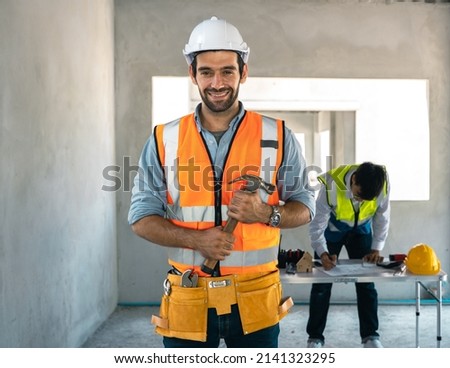 Middle Eastern engineer holding a wrench in a personal protective suit ready for construction work.
A construction project manager is smiling in a house under construction.Wearing a hard hat, vest. Royalty-Free Stock Photo #2141323295