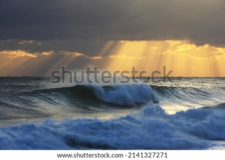 Sunrise view of sea wave spray with sunshine and dark clouds in the background at Jeongdongjin Beach near Gangneung-si, South Korea 
