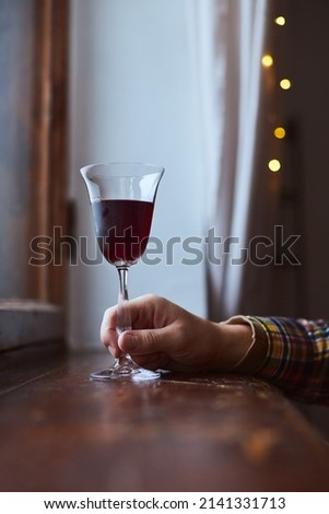 A young man drinks red wine from a vintage glass in an old mansion. Vertical photo.