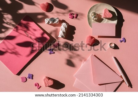 Home office desk with stationery, sweets. Pastel pink shadow background. 