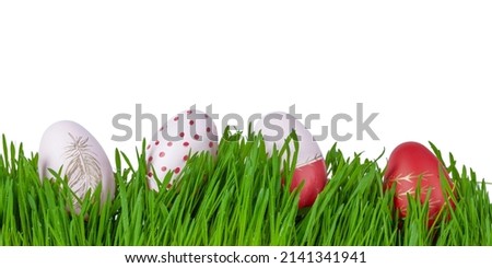 Colourful pink and red easter eggs in green grass, on white backround