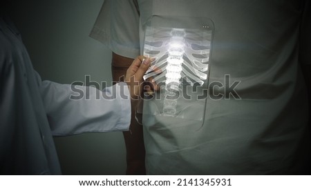 Futuristic concept of a doctor using an advance transparent x-ray pad scanning a patient's backbone looking for a sign of spinal disc herniation
