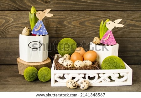 Easter decorative composition, home decoration.  On a wooden background, spring flowers, Easter eggs, cute rabbits, Easter eggs, green decorative balls.  The concept of a bright Easter holiday.