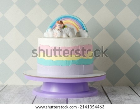 beautiful colorful children's birthday cake for a girl. cake with a rainbow, clouds and a figurine of a girl. the concept of a children's holiday