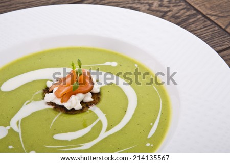 Bowl of healthy green pea soup topped with cream and fresh 