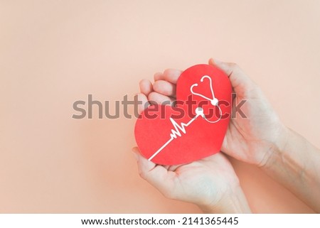 hand holding red heart with heartbeat and stethoscope icon on grunge orange pastel background for health check up concept including copy space Royalty-Free Stock Photo #2141365445