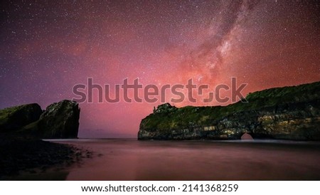 Milky Way galaxy rising over sunset sky with sea and cliff in foreground, South Africa