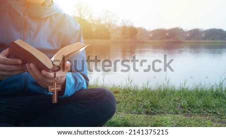 Man Reading Bible By Lake in the morning Royalty-Free Stock Photo #2141375215