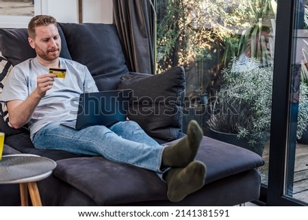 Calm adult man, looking at his laptop, checking the bank benefits, online.