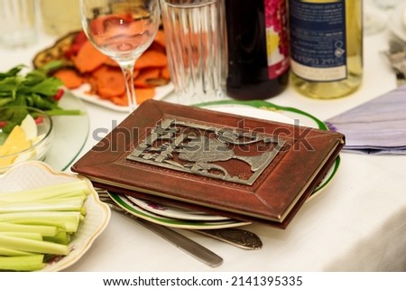 Table with Passover Haggadah and traditional food that is eaten in the Passover Seder. Seder Plate and Passover Haggadah Prepare to Pesach Seder. Royalty-Free Stock Photo #2141395335