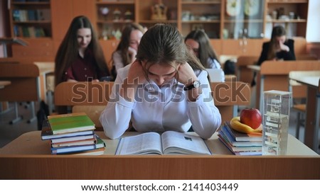 A hardworking student sits at a desk with books at school. Royalty-Free Stock Photo #2141403449