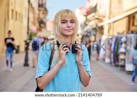 Young woman in headphones with backpack on street of tourist city