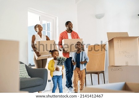 African american family with two children carrying boxes in a new home. Cheerful mature mother and mid adult father holding boxes while entering new house with son and daughter with copy space. Royalty-Free Stock Photo #2141412467