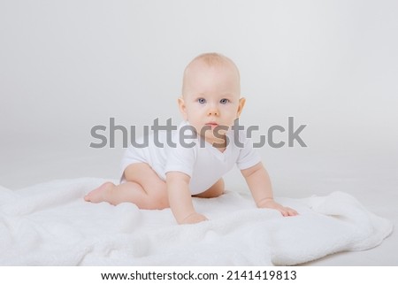a baby in a white bodysuit crawls on a white background