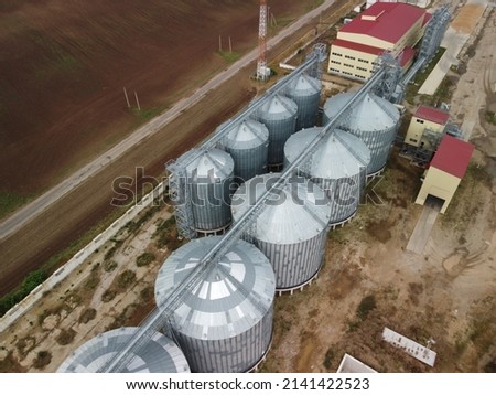 Grain elevator. Metal grain elevator in agricultural zone. Agriculture storage for harvest. Grain elevators on green nature background. Exterior of agricultural factory. Nobody.