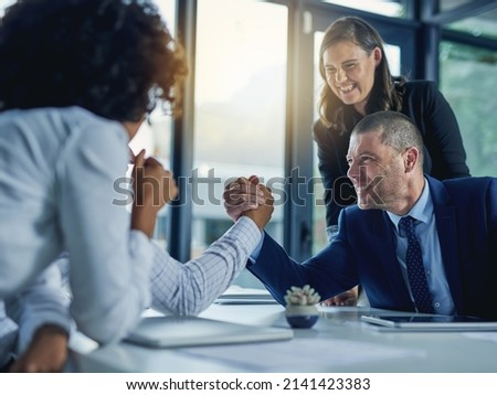 Theyre at loggerheads. Shot of two businesspeople arm wrestling during a meeting in the boardroom.