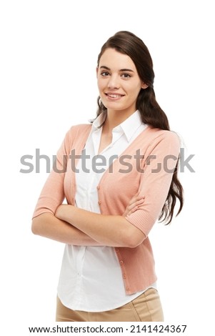 Calm and composed. Cropped view of a preppy young woman standing against a white background with her arms folded.