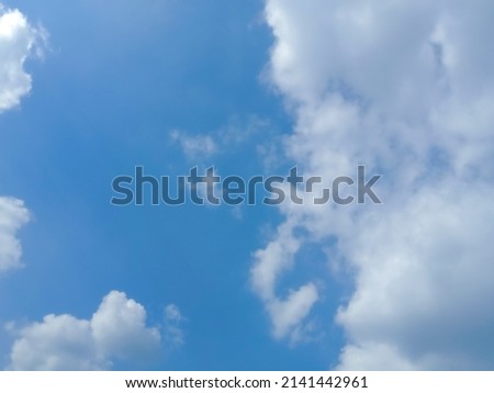 Beautiful white flat puffy clouds on deep blue sky background. Elegant blue sky picture in daylight. Big soft white fluffy clouds in the blue sky background. Cumulus clouds in deep blue sky. No focus
