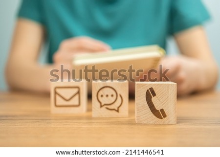 Customer service concept background. Call center, assist and support, cooperation. Wooden cubes with message icons and young woman hands in office photo
