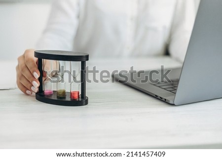 Female working on laptop at office, hourglass measuring time, efficiency at work, stock footage