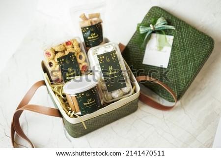 Ramadhan gift. Hampers moslem theme for celebrete the holy, bake snack, nastar, bakery, cookies, pudiing, chococips, roll cake, castangel.with greeting card and green accessories on white background Royalty-Free Stock Photo #2141470511